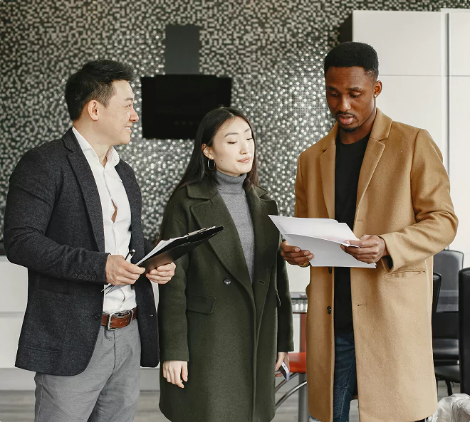 Three professionals standing and discussing documents in a modern office